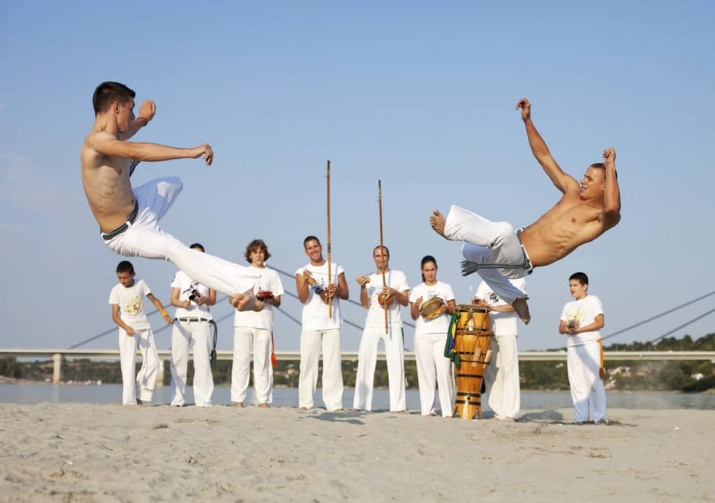 Group of people performing capoeira on the beach.
